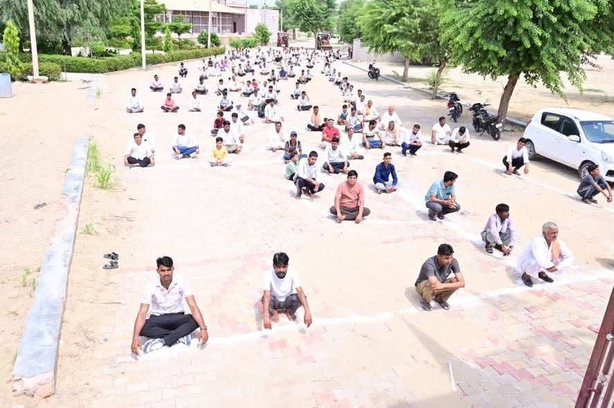 मंदिर परिसर के मैदान में कतारों में बैठे लोग
